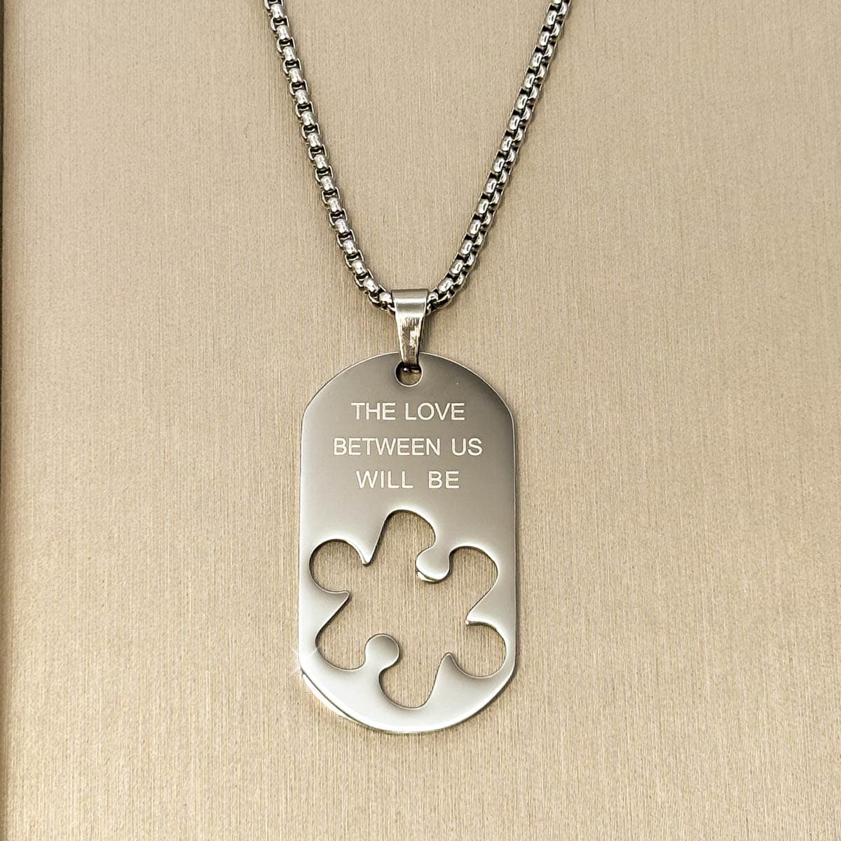 Herren-Halskette mit silberfarbenem Dog-Tag-Anhänger, Gravur und ausgestanzter Puzzleteil-Form aus Edelstahl, Nahaufnahme.
