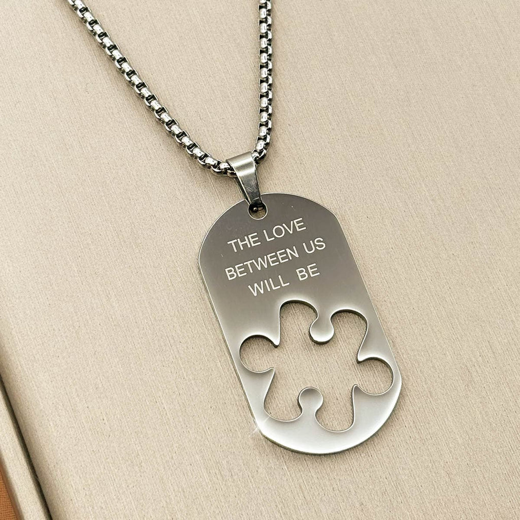 Herren-Halskette mit silberfarbenem Dog-Tag-Anhänger, Gravur und ausgestanzter Puzzleteil-Form aus Edelstahl, Nahaufnahme.