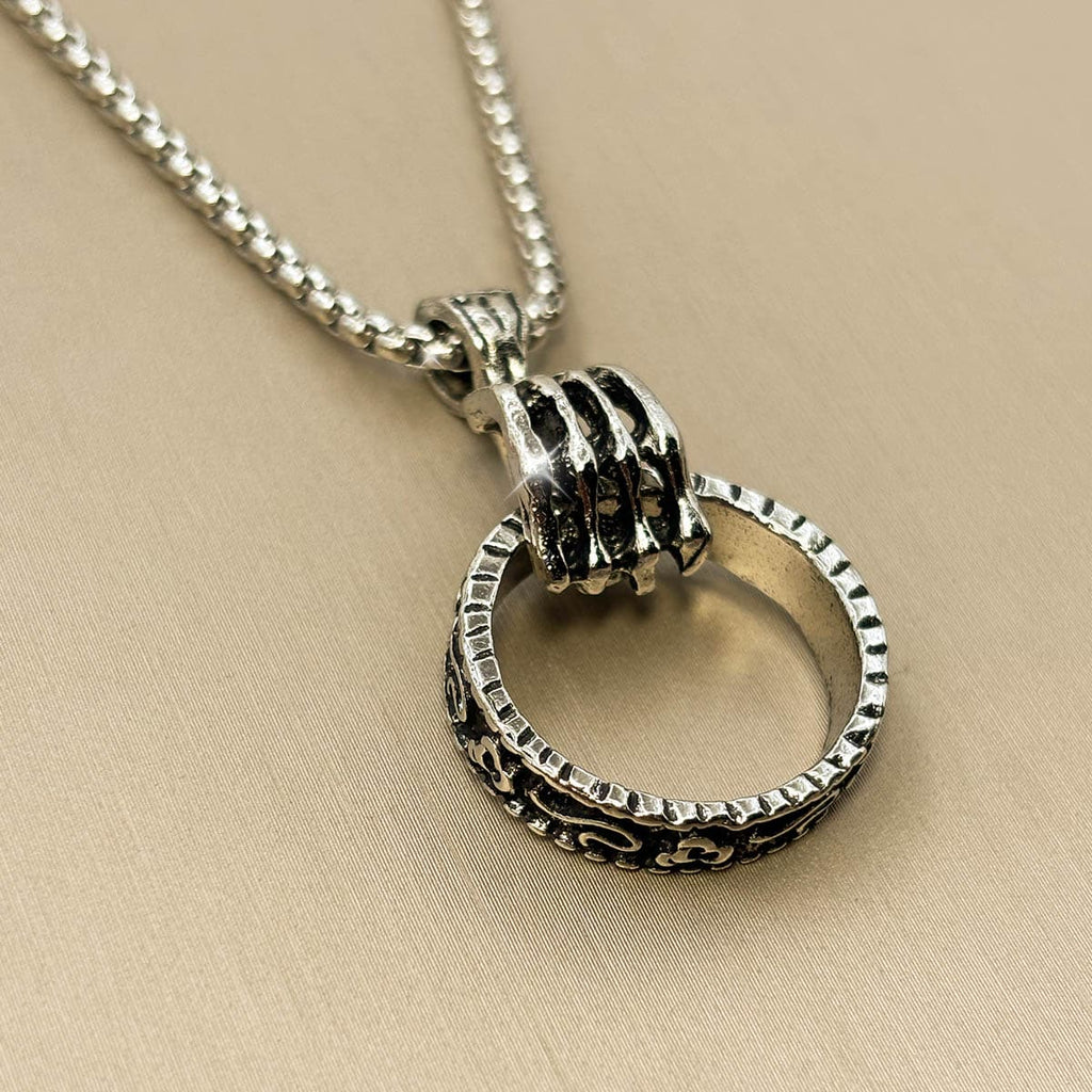 Silberfarbene Edelstahl-Herrenkette mit einem Anhänger in Form einer Hand, die einen strukturierten Ring greift, Studioaufnahme.