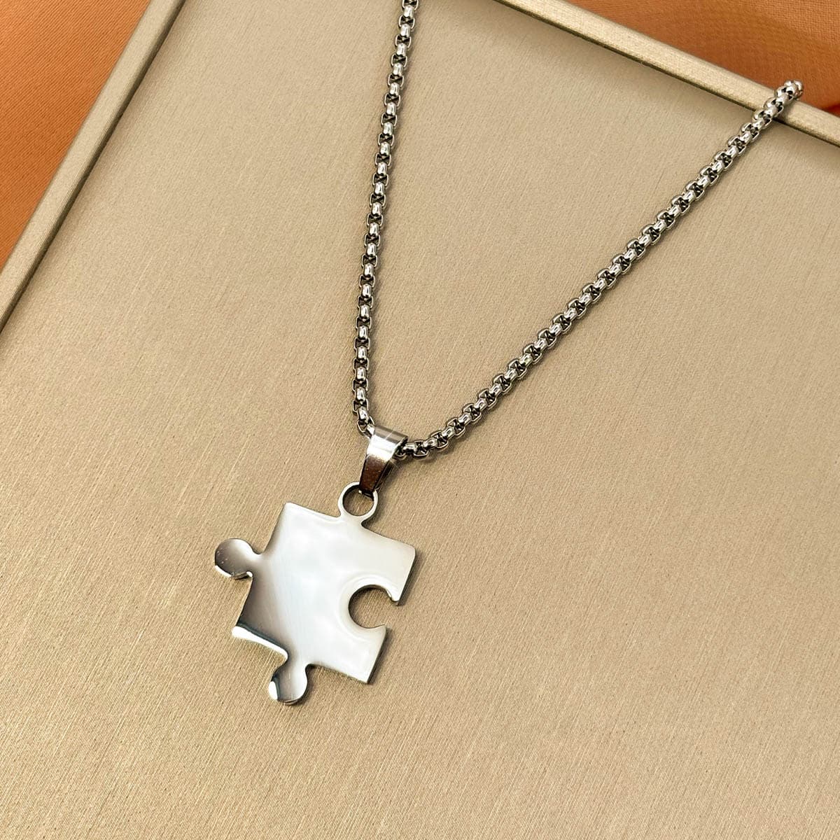 Silberfarbene Herren Halskette aus Edelstahl mit einem Partner Puzzle Anhänger, Nahaufnahme von links.