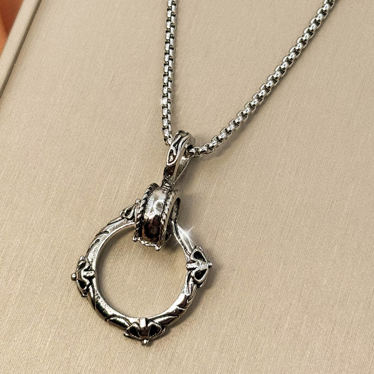 Silberfarbene Edelstahl Herrenkette mit einem Gothic Ring Anhänger, Studioaufnahme von rechts.